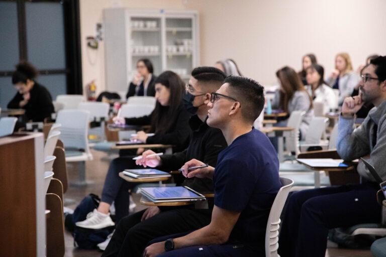 A classroom full of SCU students taking notes and listening to a lecture.