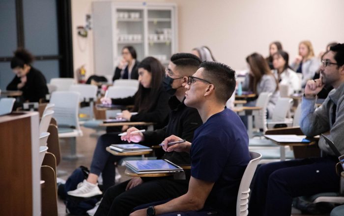 A classroom full of SCU students taking notes and listening to a lecture.