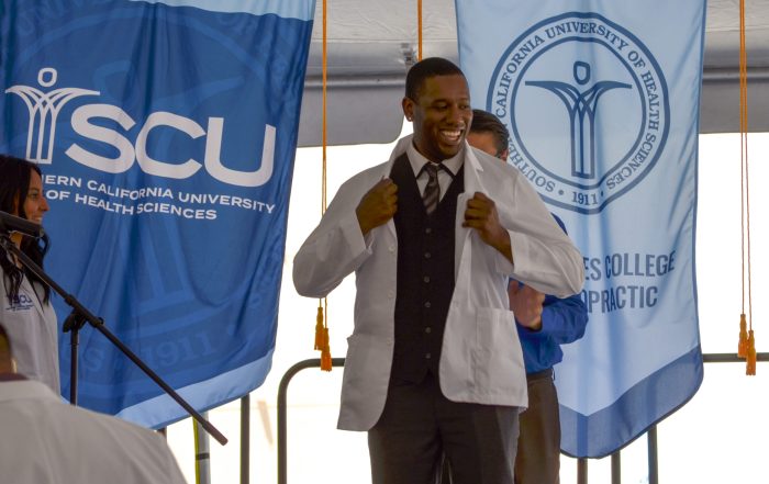 A SCU student is coated with his first, ever White Coat at the SCU Fall 2022 White Coat Ceremony